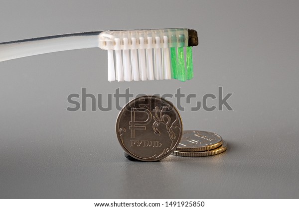 the brush hovered over a metal coin on a gray background. even lay two coins