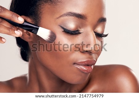 Brush on more of your beauty. Studio shot of a beautiful young woman applying blush with a makeup brush.