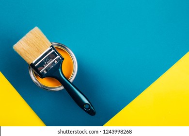 Brush On Open Can Of Yellow Color Paint On Yellow And Blue Background. Flat Lay Style. Renovation Concept.