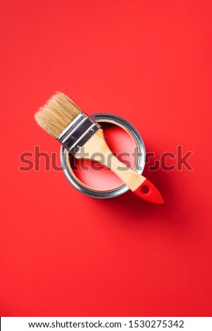 Brush and open paint can on trendy red background. Top view, copy space. Appartment renovation, repair, building and home design concept