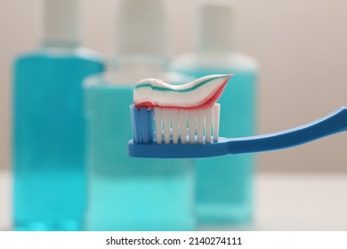 Brush with toothpaste on blurred background, closeup