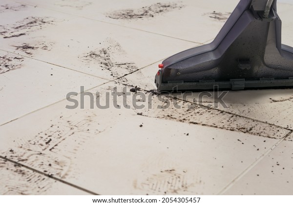 the brush of the washing vacuum cleaner removes\
the traces of the sole of the shoes on the floor of the ceramic\
tile, close-up