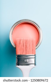 Brush With White Handle On Open Can Of Living Coral Paint On Blue Pastel Background. Color Of The Year 2019. Main Trend Concept.