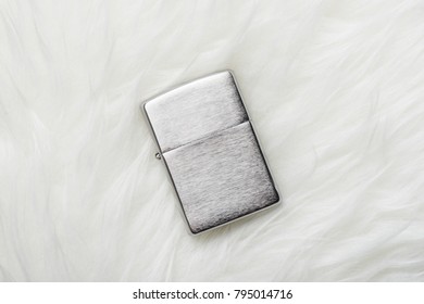 brushed chrome lighter with windproof isolated over white fur.