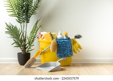Brushes, bottles with cleaning liquids, sponges, rag and yellow rubber gloves on white background. Cleaning supplies in the yellow bucket on the wooden floor. Cleaning company service advertisement - Shutterstock ID 2243557579