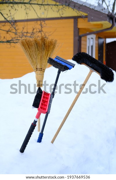 Brushes for cleaning the car\
from snow and a broom are stuck in a snowdrift. Selective\
focus.