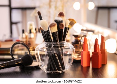 Brushes and different cosmetics on table of makeup artist