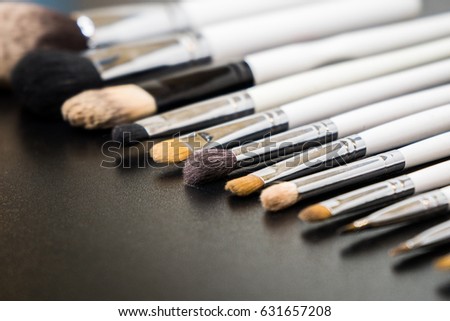 Brushes for make-up with a white plastic handle isolated on a black background or lie on the surface of the table.