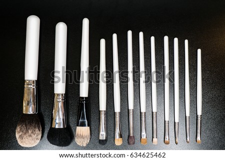 Brushes for make-up with a white plastic handle isolated on a black background or lie on the surface of the table.