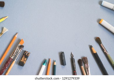 Brushes, pencils, markers lie on a blue background - Shutterstock ID 1291279339
