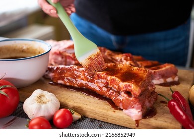 Brushing Pork Ribs With Marinade Sauce On Wooden Cutting Board