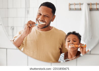 Brushing teeth, father and child in a home bathroom for dental health and wellness with smile. Face of a man and african boy kid learning to clean mouth with a toothbrush and mirror for oral hygiene