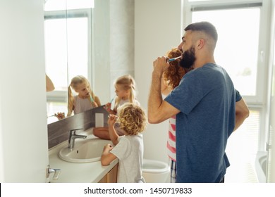 Brushing Teeth. Nice Bearded Man Putting A Brush In His Mouth While Brushing Teeth Together With His Family