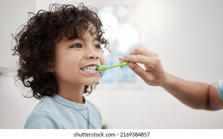 Brushing your kids teeth properly helps prevent cavities and infection. Shot of a father brushing his little sons teeth in the bathroom at home. - Powered by Shutterstock