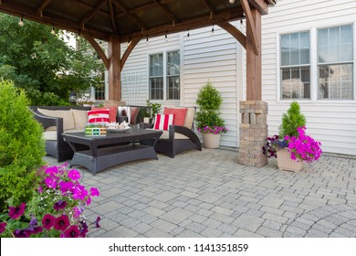 Brussel block design pavers on an exterior patio and summer living space with a covered gazebo, colorful petunias and comfortable seating