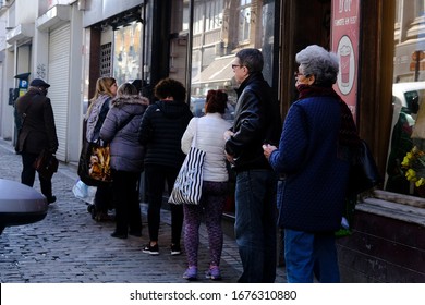 Brussels, Belgium. 18th March 2020. Shoppers Stand In A Queue Outside A Supermarket Before Belgium Government Imposes A Coronavirus Lockdown.