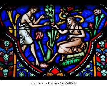 BRUSSELS, BELGIUM - JULY 26, 2012: Adam and Eve eating the Forbidden Fruit in the Garden of Eden on a stained glass window in the cathedral of Brussels.
