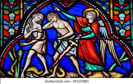 BRUSSELS, BELGIUM - JULY 26, 2012: Adam and Eve expelled from the Garden of Eden on a stained glass window in the cathedral of Brussels, Belgium. 