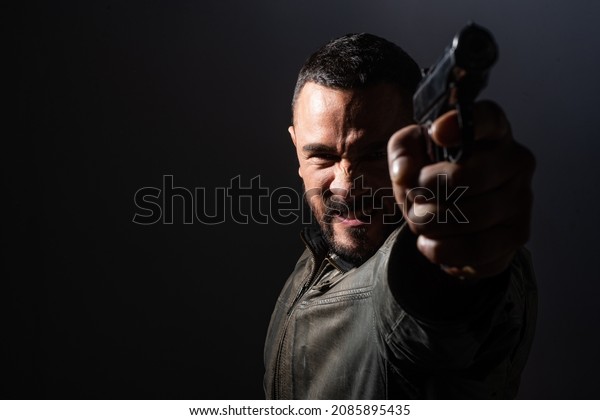 Brutal angry gang man lifestyle. Gangster in\
action, killer aiming pistol gun. Guy shooting firearm handgun,\
makarov pistol in a firing\
range