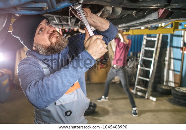 Brutal bearded car\
mechanic works in the garage.The master is repairing the car.\
Repairman in the garage.