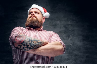 Brutal Bearded Male With Tattooed Arm Wearing Santa's New Year Hat.