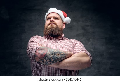 Brutal Bearded Male With Tattooed Arm Wearing Santa's New Year Hat.