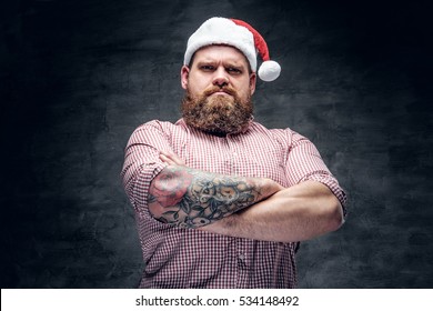 Brutal Bearded Male With Tattooed Arm Wearing Santa's New Year Hat.