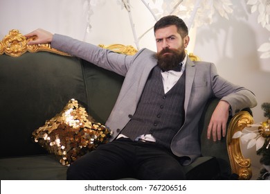 Brutal Bearded Man Sitting In Comfortable Sofa. Handsome Bearded Man In Suit On Luxurious Couch. Arrogant Rich Bearded Man, Sexy Male, Bisnessman.