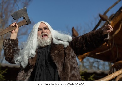 Brutal Druid Old Man With Long Silver Hair And Beard In Fur Coat With Axe In Hand On Blue Sky Background