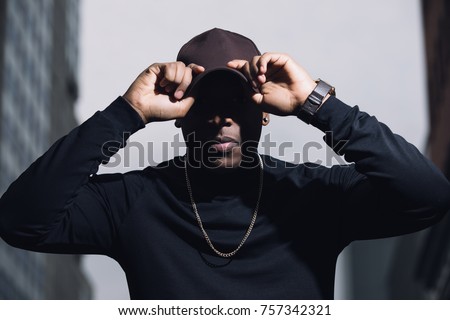 Brutal man rapper with cap posing in city