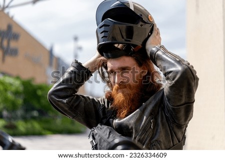 brutal red bearded biker sitting on a black motorcycle after a race takes off his helmet lust speed motorsport concept