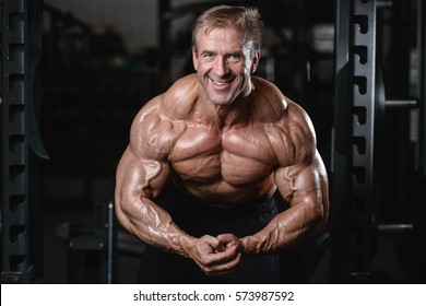 Brutal Strong Athletic Old Man Pumping Up Muscles And Train In Gym Workout Bodybuilding Concept Background - Muscular Bodybuilder Handsome Men Doing Exercises In Gym Naked Torso