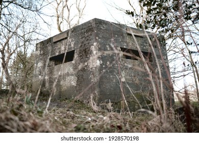A brutalist cold gritty concrete world war two, ww2 pillbox war bunker defence fortress in a dirty forgotten woodland in europe. wartime relics and forgotten outpost using solid architecture to defenD