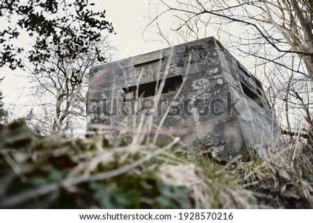 A brutalist cold gritty concrete world war two, ww2 pillbox war bunker defence fortress in a dirty forgotten woodland in europe. wartime relics and forgotten outpost using solid architecture to defenD