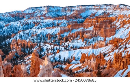 Bryce Canyon National Park in Utah (USA). Giant natural amphitheater panorama at sunrise on a cold winter morning. “Hoodoo“ structures, formed by frost and stream erosion with snow and warm light.