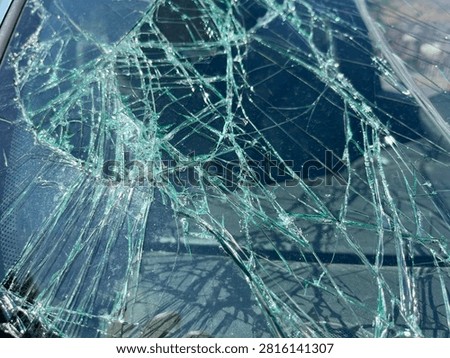 bstract Close Up of Shattered Car Windshield Glass Texture
 Macro detail of cracked and shattered car windshield glass with green tint and spiderweb pattern.