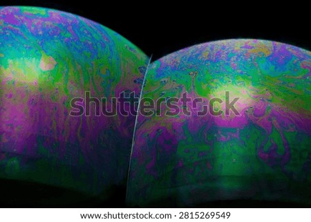 bstract macro view of soap bubble surfaces displaying iridescent rainbow color patterns and swirling liquid textures on a black background