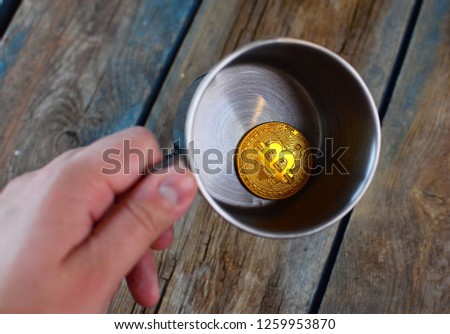 BTC symbol. Bitcoin at the bottom of the metal cup. Bitcoin falling and shattered dreams about the wealth concept. 