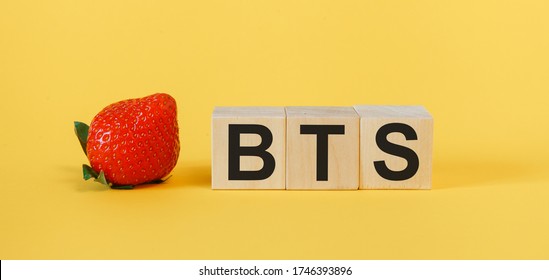 BTS concept with wooden cubes. The word BTS on a yellow background