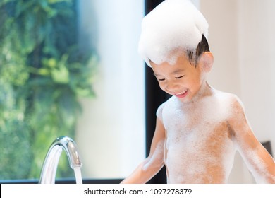 Bubble Bath time. Asian boy in bathtub with fluffy soap bubble. Adorable little boy have fun time with bubble bath in hot summer day. Concept for imagination sensory play.