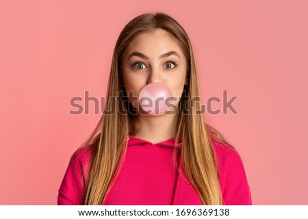 Bubble from chewing gum. Teenage girl on pink background