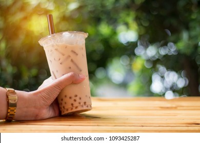 Bubble Ice Milk Tea Served In Takeaway Glass With Green Bokeh Background 