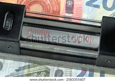Bubble level on euro banknotes shows a clear downward tilt – a striking symbol of the struggling economy and increasing financial pressure.