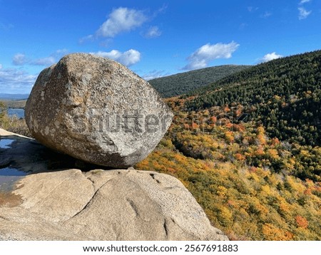 Bubble rock appears to be balanced on the top of a mountain cliff and is a popular hiking destination in Acadia National Park, Maine on a an autumn day 