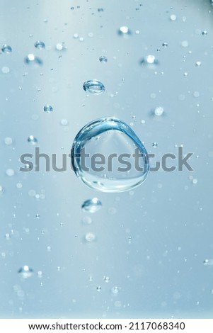 Bubbles of air or oxygen in water or gel. Can also represent a molecule or oil particle in a transparent liquid. Round and blue floating bubbles similar to hyaluronic acid. Shallow depth of field.