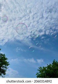 Bubbles flying infront of a cloudy sky.