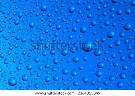 Bubbles and water drops in selective focus on glass, blue background. 