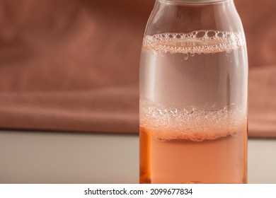 Bubbling Bi-Phase Makeup Remover. Mixing Of Two Liquids Of Different Density And Color. Bottle With Two-color Liquid On A Pink Background.