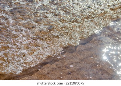 Bubbling Small Waves Breaking In Shallow Water On Beach In Sunlight With Motion Blur  And Selective Focus Background