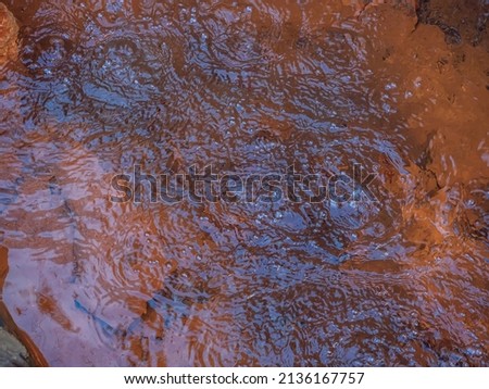 Bubbling water of a mineral natural spring against the background of a red rocky bottom. Full screen photo